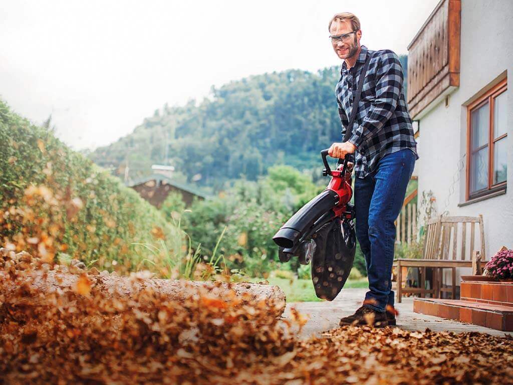 a man blows away leaves in front of the front door