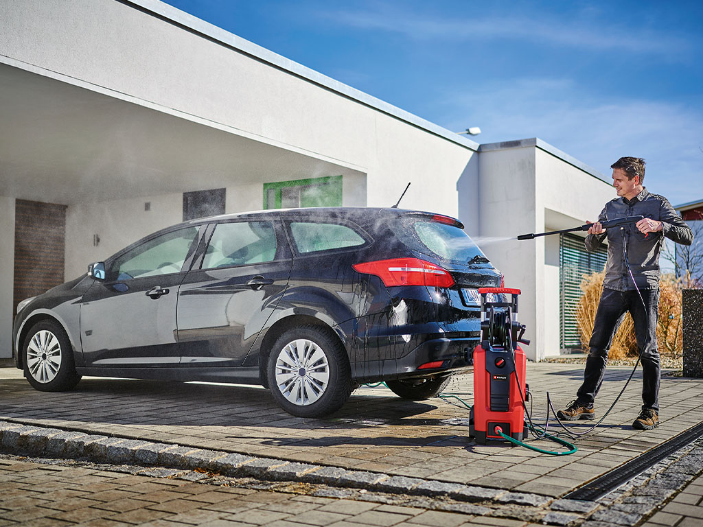 A man cleans a car with a Einhell high pressure cleaner