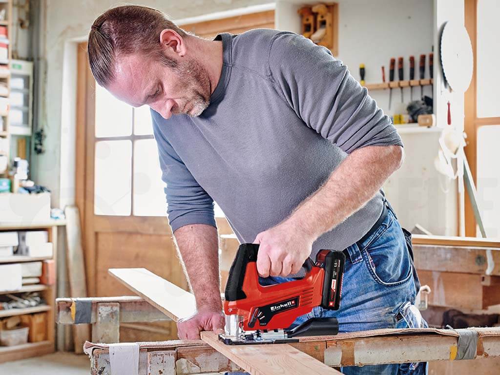 man cuts wooden board with a jigsaw