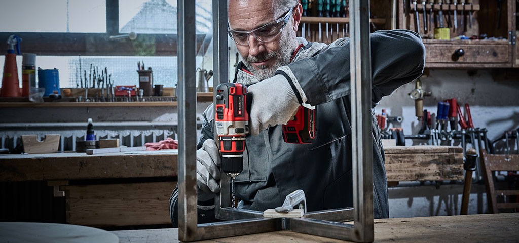 Handwerker bohrt mit einer Einhell Bohrmaschine ein Loch in ein Metallprofil.
