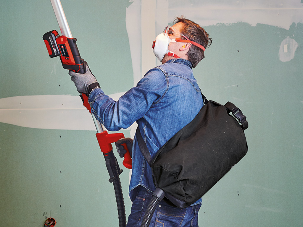 Man with drywall sander and dust bag