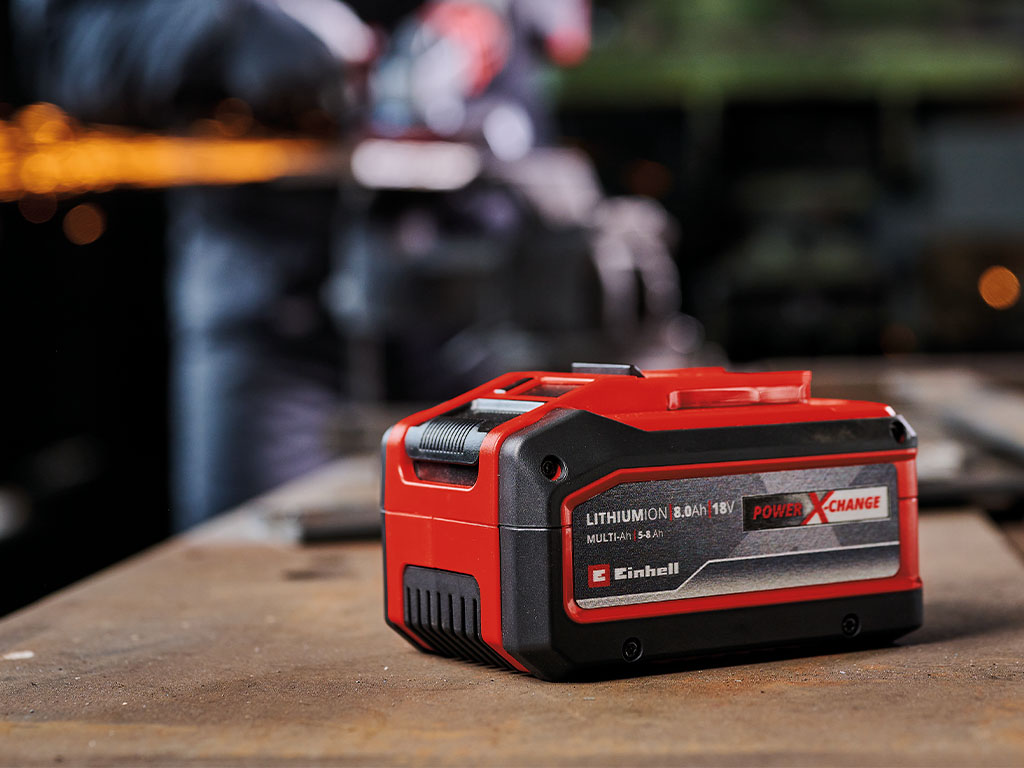 The Einhell Multi-Ah battery is placed on a workbench in a workshop