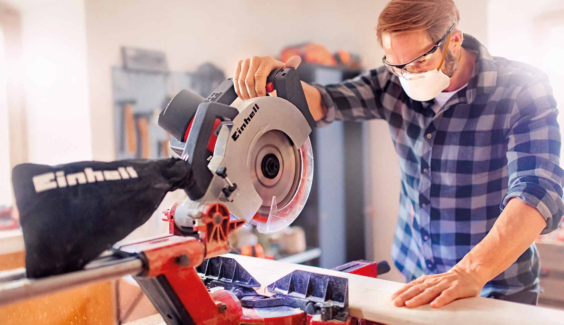 A man using a mitre saw to cut wood.