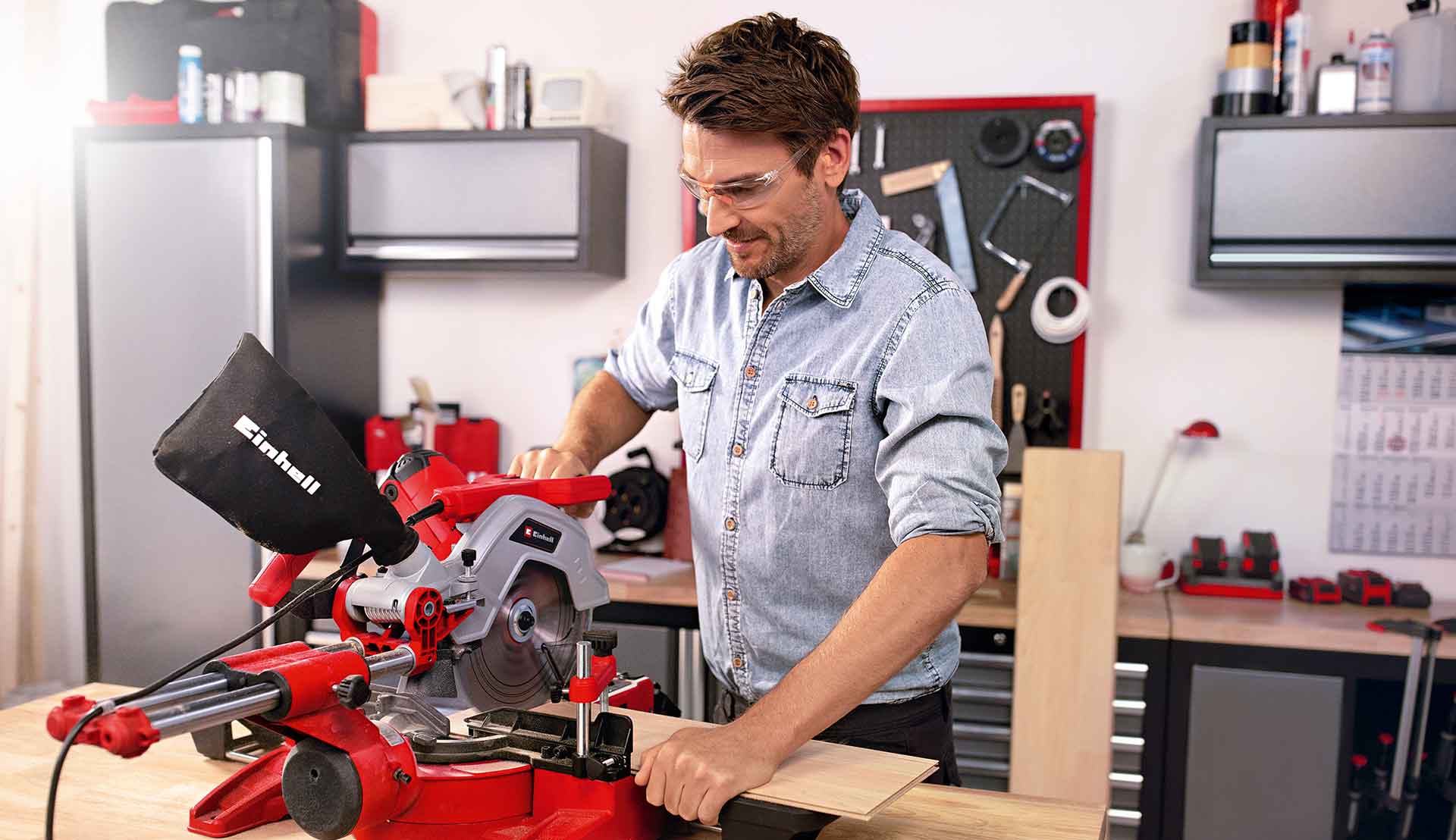 Ein Mann nutzt eine Zug-Kapp-Gehrungssäge, um in seiner Werkstatt eine Holzplatte zu sägen.