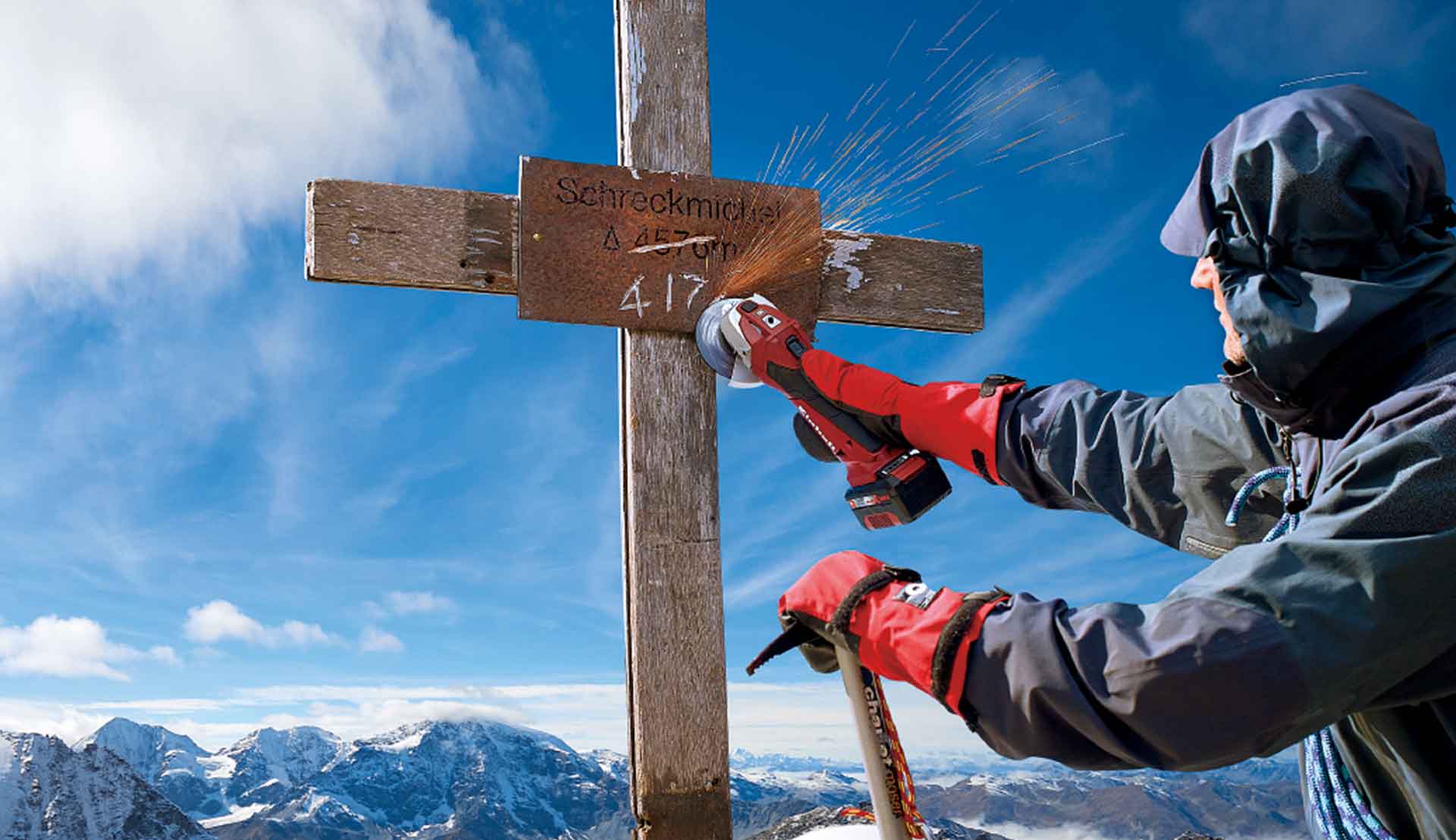 ein Mann arbeitet mit einem Einhell Akku-Winkelschleifer an einem Gipfelkreuz