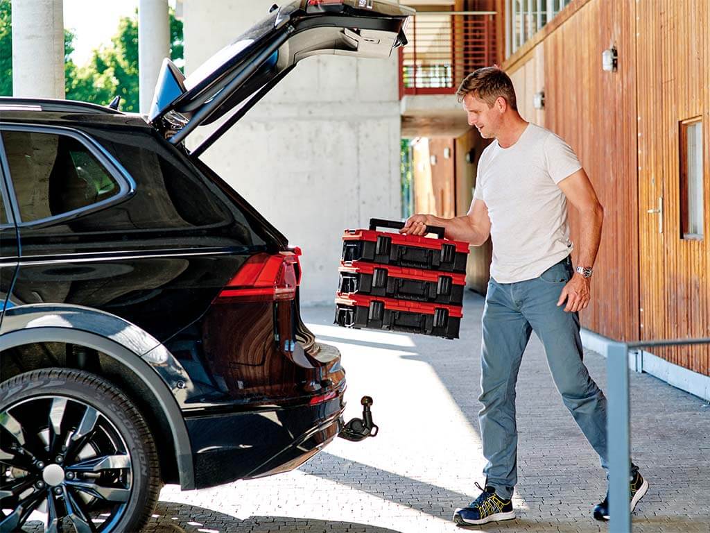 A man puts three toolboxes into a car