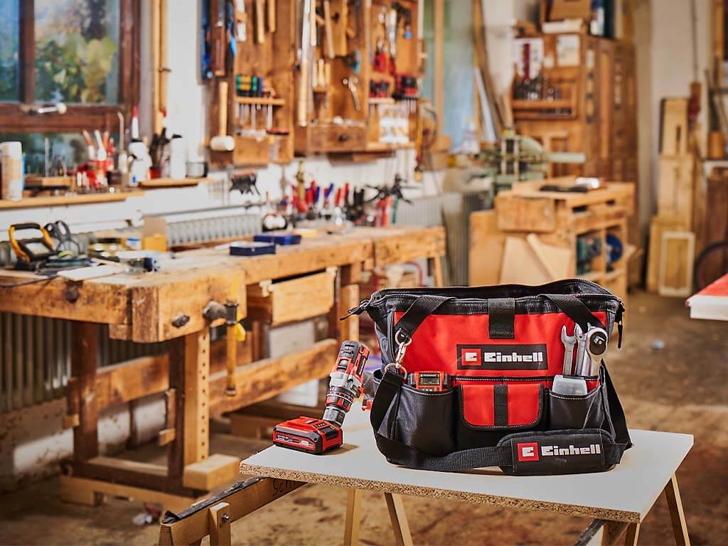 einhell bag surrounded by tools stands on a table in a workshop