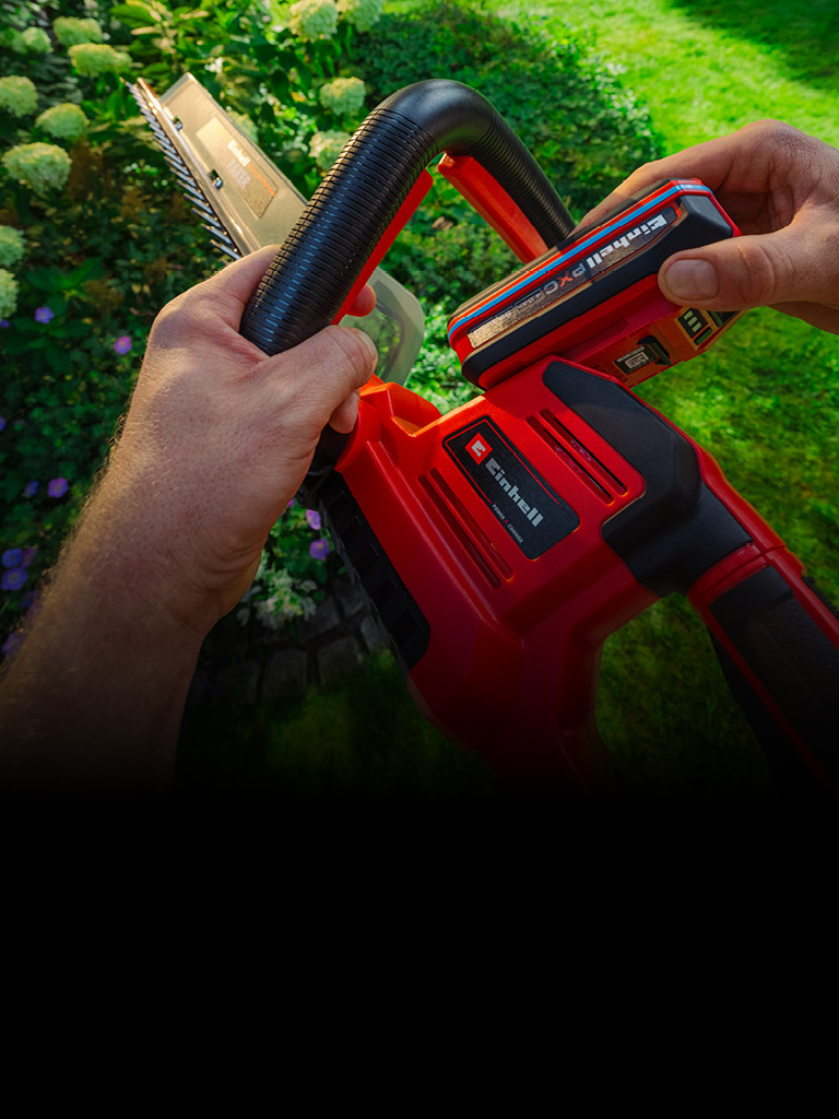 Hand setzt einen Einhell-Akku in ein Gartengerät ein.