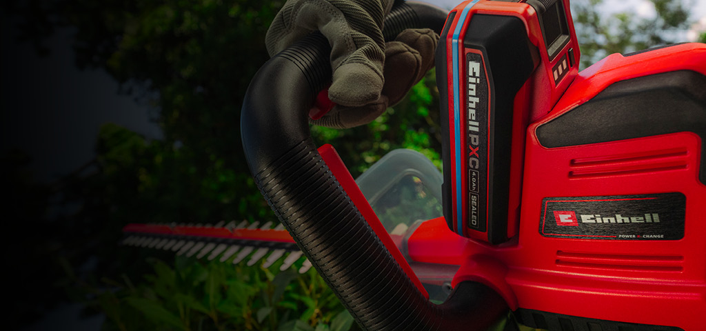 Einhell-Akku-Heckenschere schneidet Äste an einem Baum im Garten.