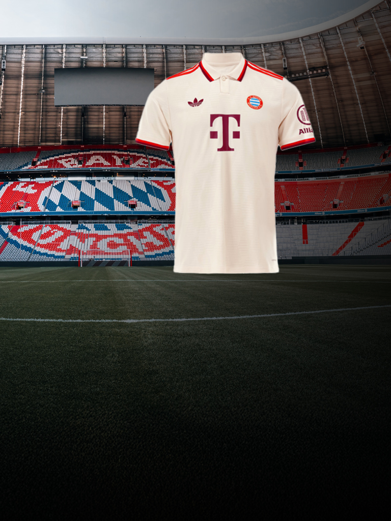 Ein cremefarbenes FC-Bayern-Trikot mit roten Details vor leeren Tribünen der Allianz Arena.