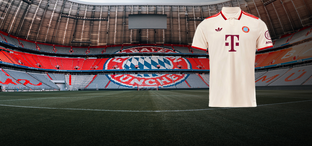 Ein cremefarbenes FC-Bayern-Trikot mit roten Details vor leeren Tribünen der Allianz Arena.