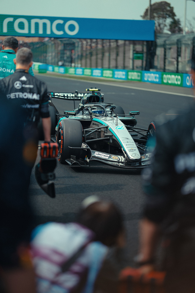 Mercedes Formel-1-Auto in der Boxengasse umgeben vom Team
