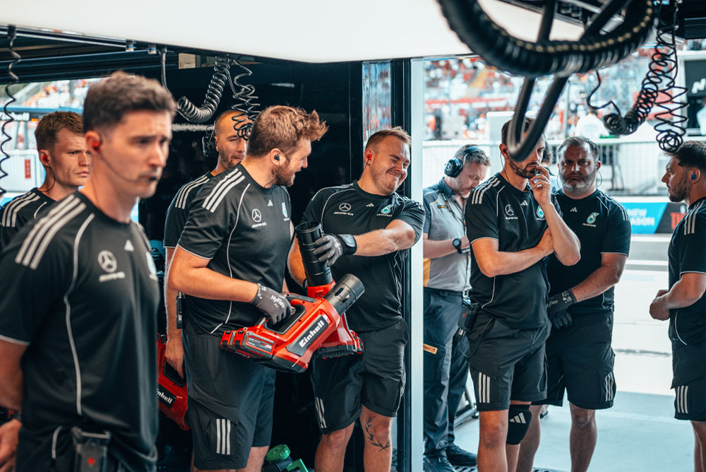 Das Mercedes-AMG PETRONAS Formel-1-Team befindet sich in der Box. Zwei Teammitglieder halten rote Akkubläser von Einhell in der Hand, bereit für den nächsten Einsatz.
