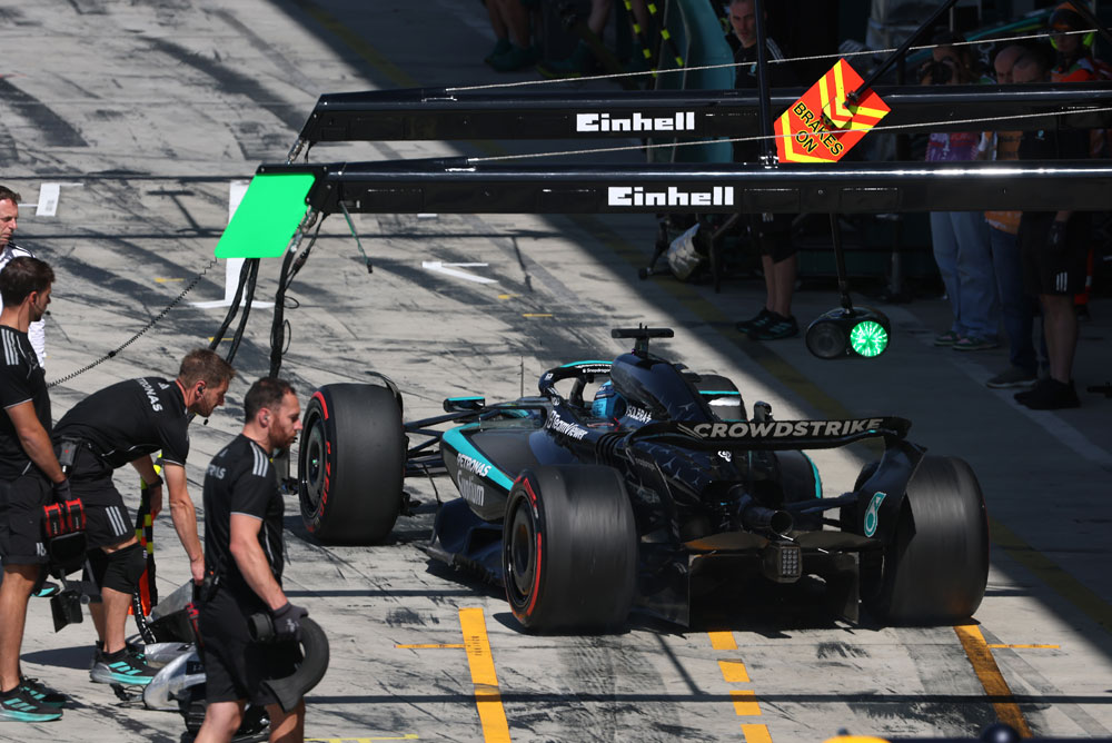 Ein Mercedes-AMG PETRONAS Formel-1-Auto in der Boxengasse bei einem Boxenstopp. Mehrere Teammitglieder stehen um das Auto. Das Einhell-Branding ist über dem Boxenbereich sichtbar.