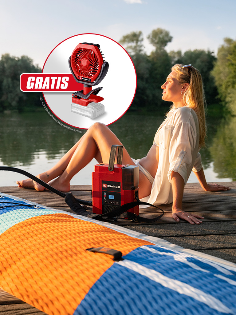Frau sitzt am See auf Steg, rotes Einhell Gerät pumpt SUP auf, Einblendung mit Ventilator und Text „GRATIS“.