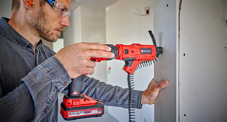 Ein Handwerker schraubt mit einem Einhell Akku-Trockenbauschrauber eine Trockenbauplatte an eine Wand.