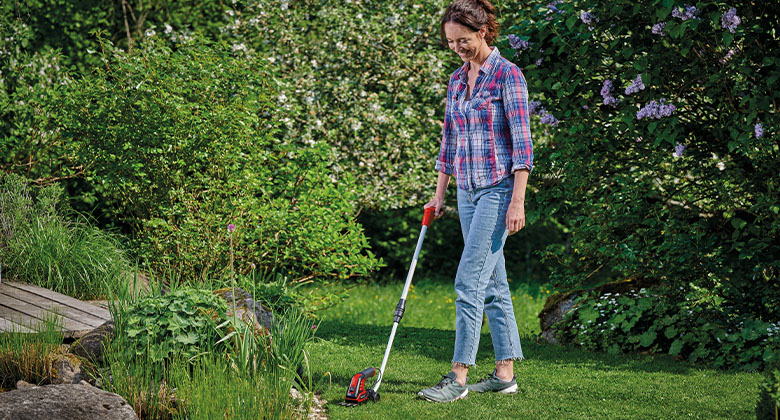 eine Frau schneidet Rasenkanten mit einer Einhell Akku-Gras- und Strauchschere