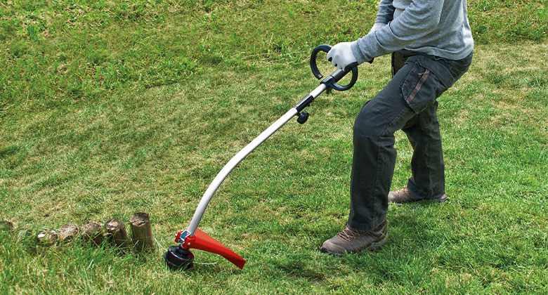 Ein Mann schneidet das Gras auf einer Wiese mit dem Einhell Benzin-Rasentrimmer