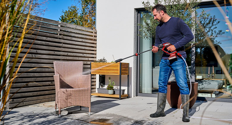 Mann reinigt einen Gartenstuhl mit dem Einhell HYPRESSO