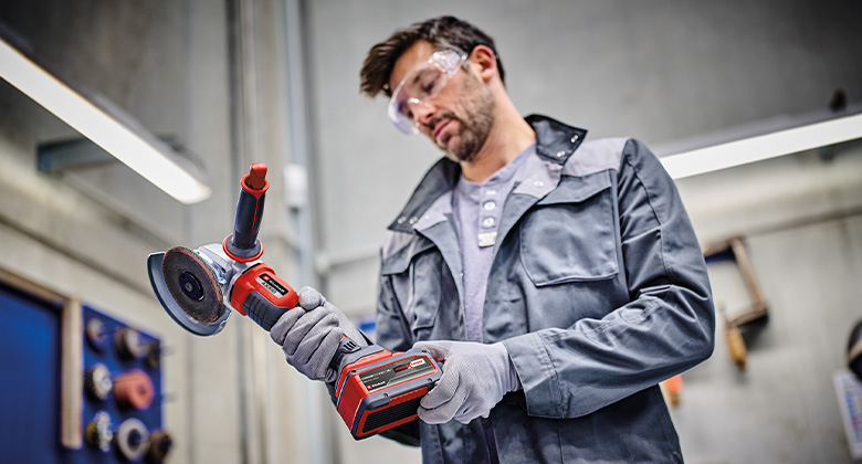 Ein Mann überprüft einen Akku-Winkelschleifer in der Werkstatt.