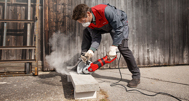 Ein Handwerker schneidet einen Betonblock mit einem kabelgebundenen Winkelschleifer.