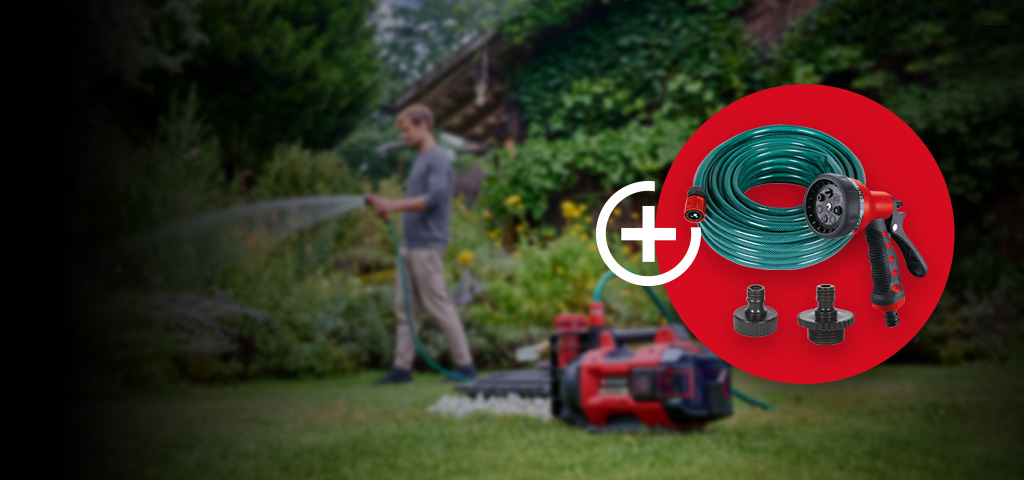 Eine Person bewässert einen Garten mit einem Gartenschlauch, während im Vordergrund eine rot-schwarze Wasserpumpe auf dem Rasen steht. Im roten Kreis befinden sich ein aufgerollter Gartenschlauch, eine Sprühpistole sowie zwei Anschlussadapter als Zubehör.