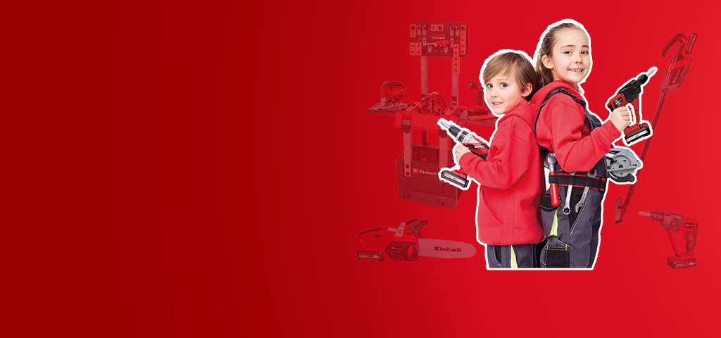 Two children in red clothing with Einhell toy tools and a workbench on a red background.