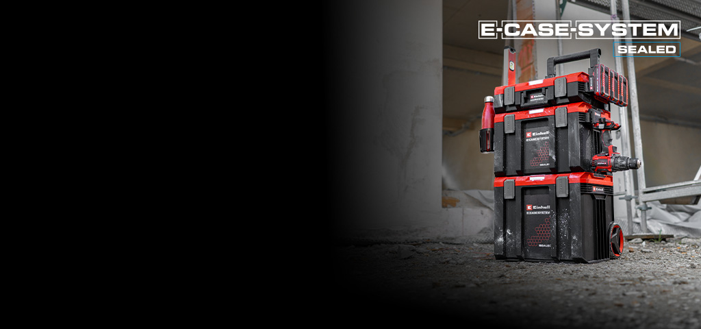 Ein Stapel von Einhell SEALED E‑Cases steht auf einer Baustelle vor einem Gerüst. Die robusten Koffer sind sicher miteinander verbunden und für die mobile Werkzeugaufbewahrung ausgelegt.